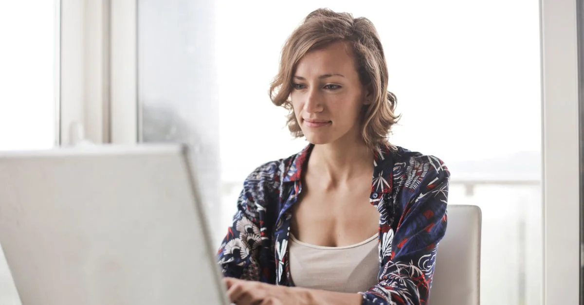 Une femme tapant sur un ordinateur portable dans un cadre de bureau à domicile lumineux et moderne.