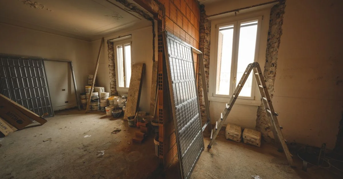 Vue intérieure d'une pièce en rénovation avec des matériaux de construction et une échelle.