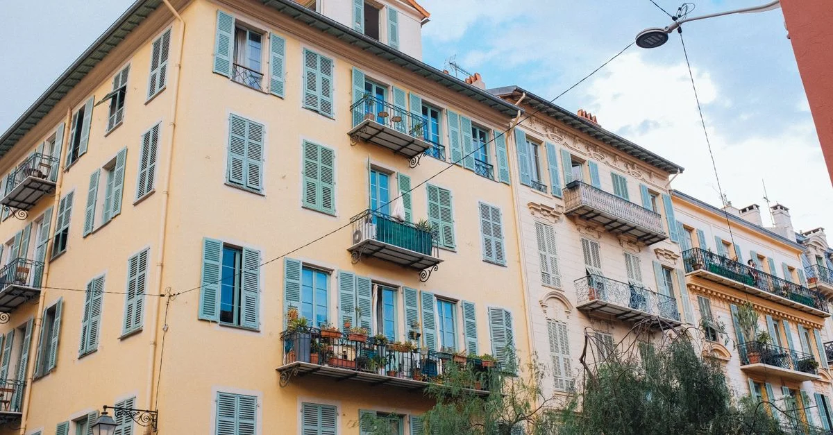 Immeuble d'appartements européen coloré avec volets et balcons contre un ciel dégagé.