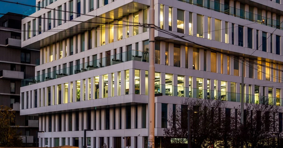 Un immeuble de bureaux moderne à l'intérieur illuminé, photographié au crépuscule.