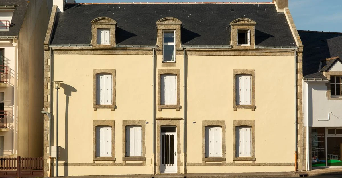 Façade historique d'une maison de ville à La Turballe, reflétant l'architecture française classique sous un doux soleil.