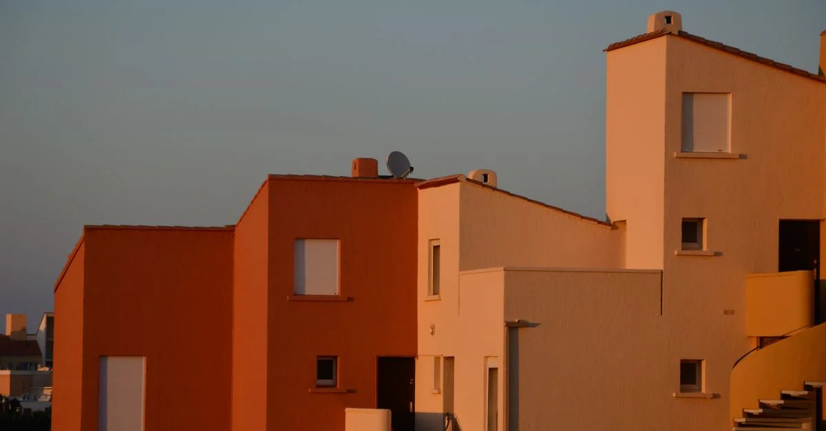 Façade d'un bâtiment résidentiel minimaliste avec la lumière du soir projetant des tons chauds sur la structure.