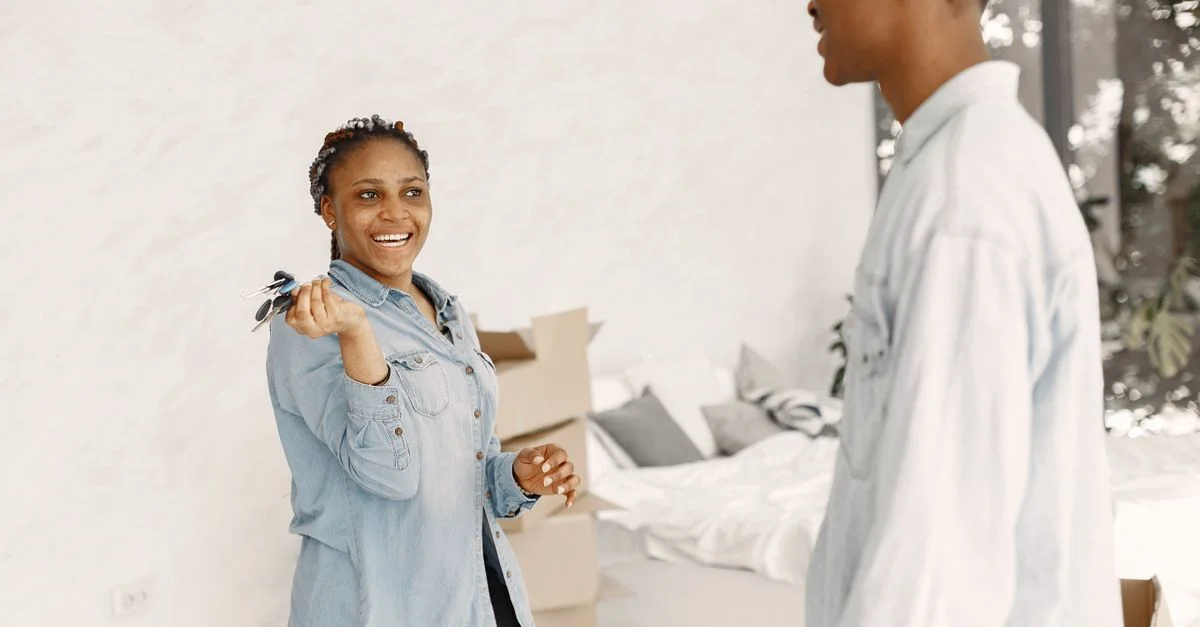 Couple souriant à l'intérieur tenant des clés, emménageant dans une nouvelle maison.