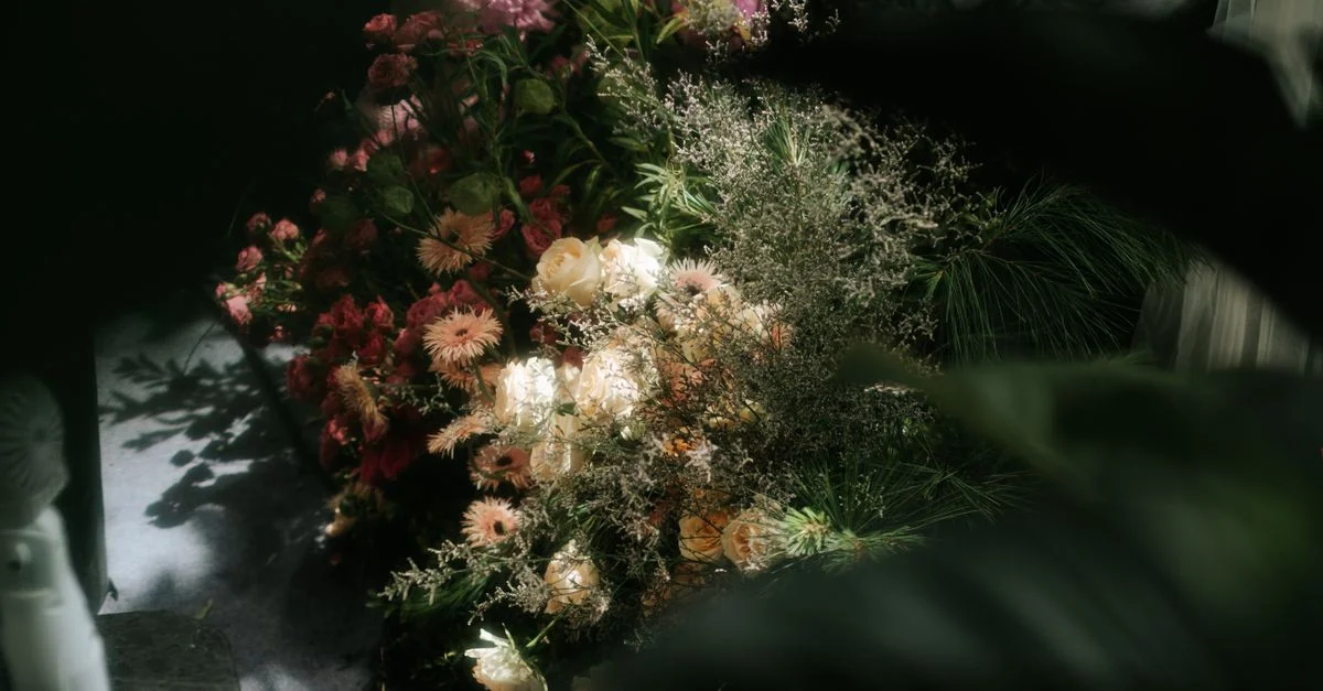 Composition florale artistique baignée d'une douce lumière naturelle aux tons pastel et chauds.