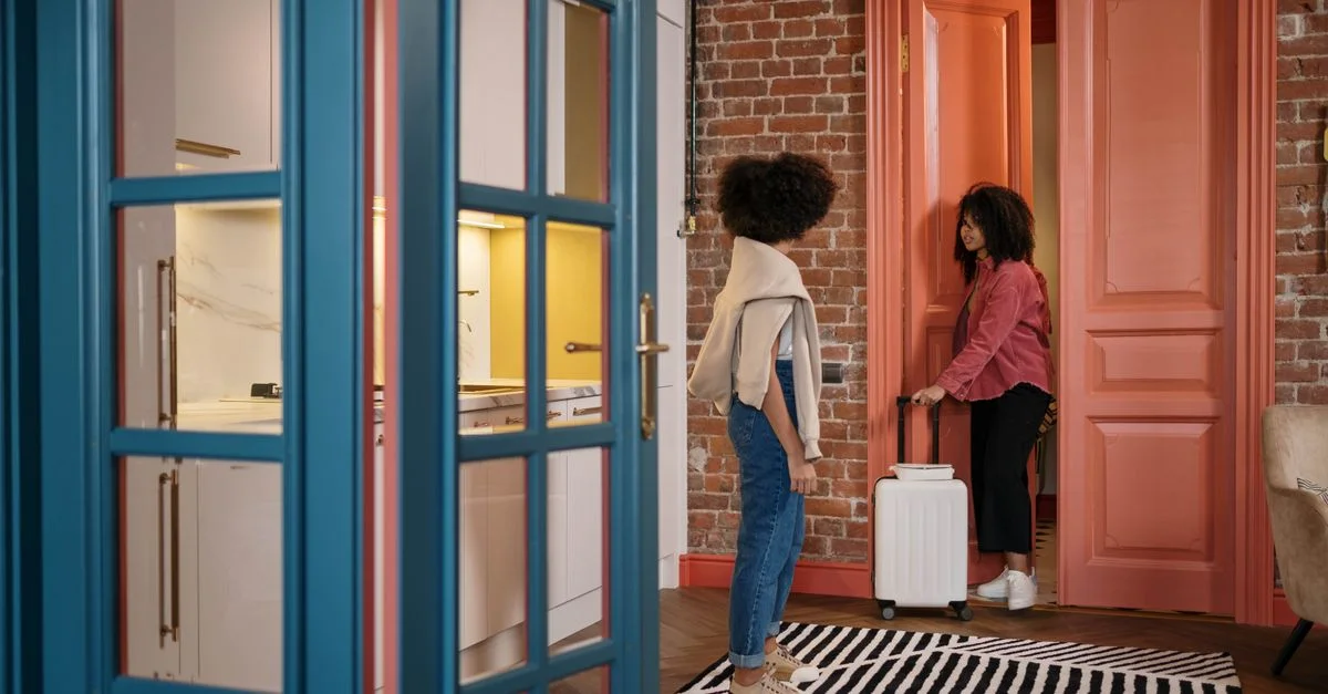 Deux femmes avec des bagages dans un couloir d'appartement stylé, se préparant à voyager.